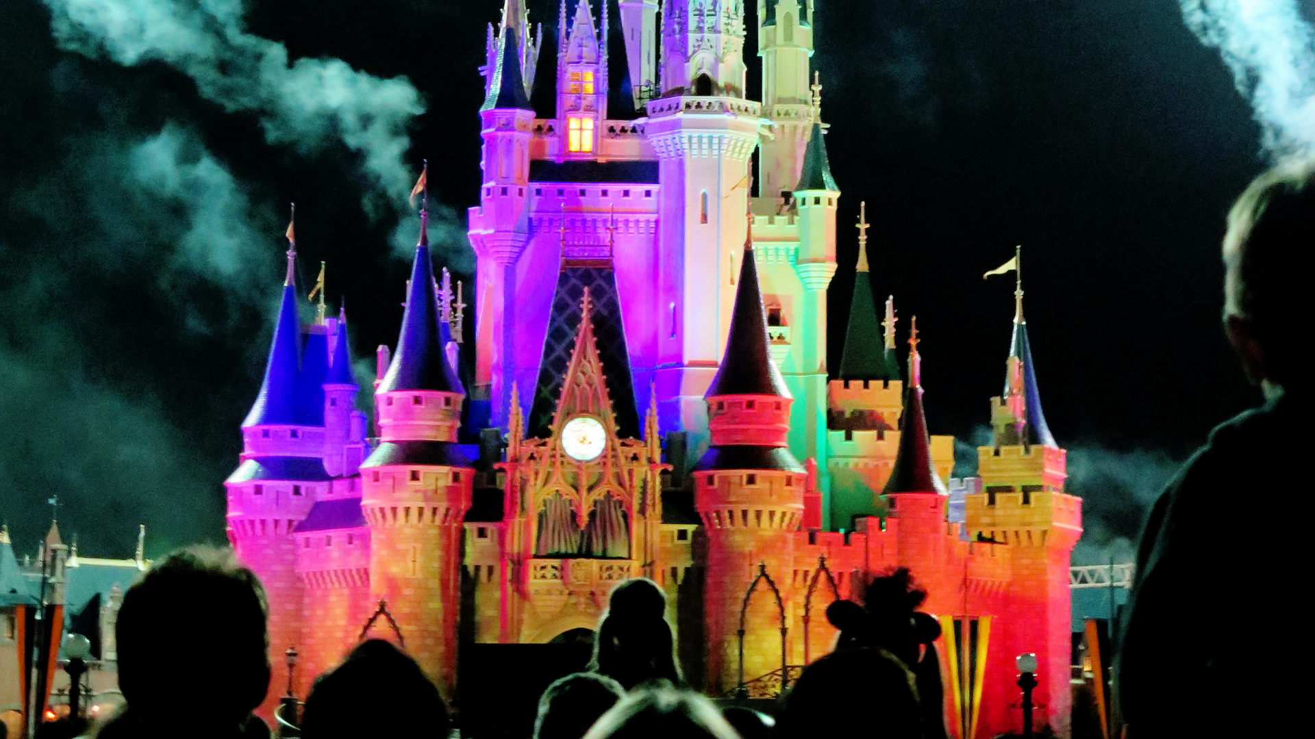 Magic kingdom castle at night, lit up with a crowd in front